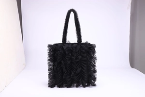 Detalle de bolso shopper de malla plisada negra con volantes y asas largas.