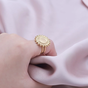 Detail of a golden round ring with sunburst texture on a purple silk background
