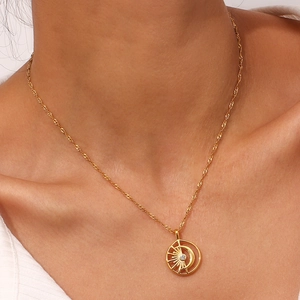 Close-up of 18K gold plated hollow sun and moon pendant with a sparkling crystal