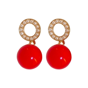 Retro gold earrings with white pearls and large red spheres on a clean white background