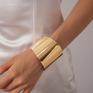 Vue macro d'un large bracelet ouvert minimaliste avec une finition miroir dorée polie