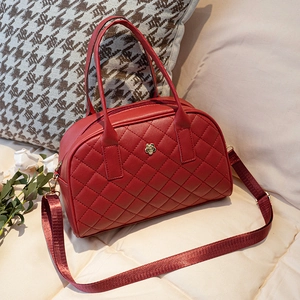 Red quilted women's handbag with gold floral hardware and adjustable strap in lifestyle setting
