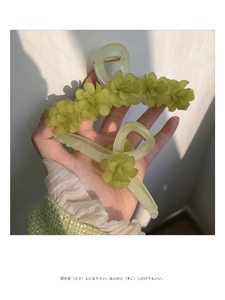 Detail of light green floral hair claws with frosted petals and metallic fringe tassels