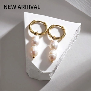 Élégantes boucles d'oreilles créoles dorées avec perles blanches sur une pierre