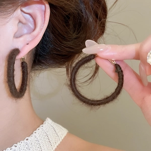 Detailed view of dark brown flocked round hoop earring with soft velvet texture
