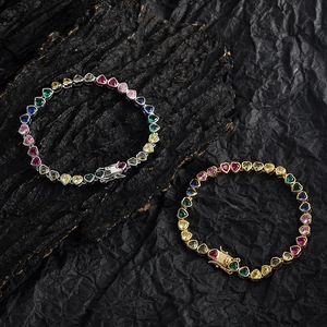 Colorful heart-cut tennis bracelets in gold and silver plating on dark stone background