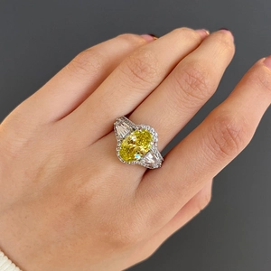 Detailweergave van een ring met ovale gele edelsteen en trapeziumvormige zij-diamanten