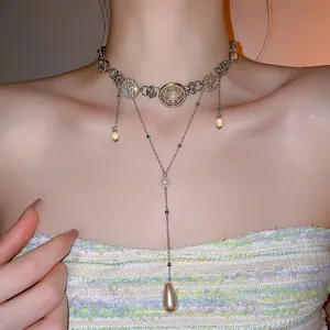 Detailed view of a Baroque Y-shaped necklace with embossed coins and amber teardrop charm