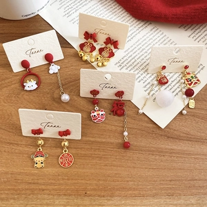 Detailed close-up of festive Chinese New Year lion dance earrings with red and gold motifs