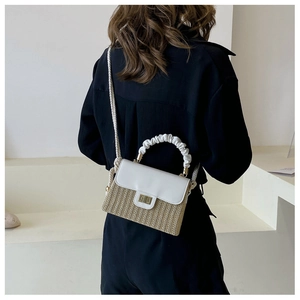 Detail of a straw and leather crossbody bag with pleated handle on a model background