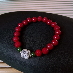 Detailed shot of S925 silver flower charm with red cinnabar beads and green jade accent