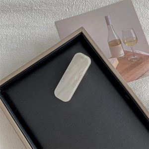 Detailed close-up of a rectangular pearlescent hair clip on a black velvet display tray