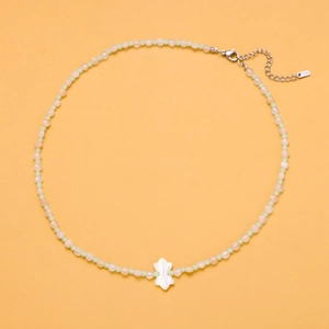 Detail of colorful beaded necklace with white butterfly pendant on yellow background