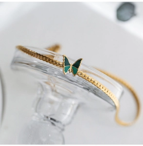 Detail of 18K gold-plated Cuban link anklet with green enamel butterfly pendant charm