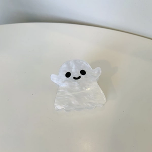 Detailed view of a ghost-shaped hair claw clip with pearlescent white acrylic finish