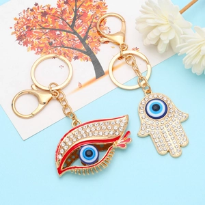 Hamsa Hand and Evil Eye gold keychains with sparkling crystals on light blue background
