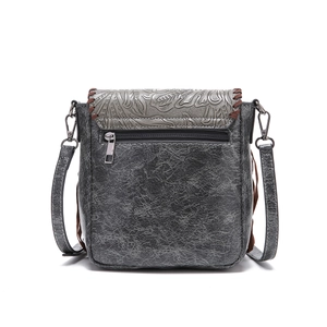 Macro view of bohemian crossbody bag featuring vintage floral embossing and leather tassels