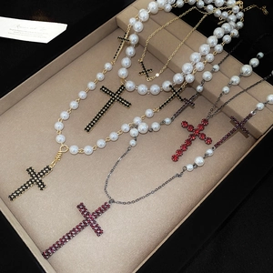 Detailansicht mehrlagige Perlenkette mit Kristallkreuz-Anhängern auf beige Tablett