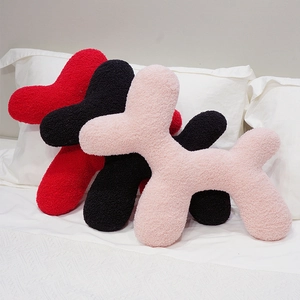 Three colorful plush balloon dog cushions in red black and pink on a white bed