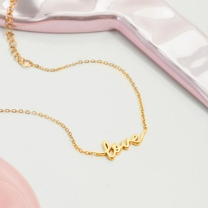 Detailed macro view of 18K gold-plated LOVE letter pendant on a fine adjustable chain