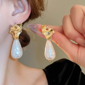 Baroque irregular pearl earrings with vintage gold geometric studs worn by a model