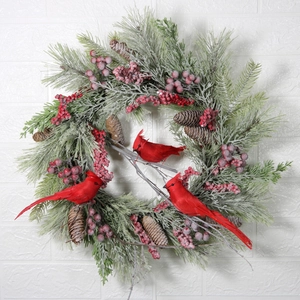 Weihnachtskranz mit Kardinalvögeln, Zapfen und frostigen Kiefernnadeln an weißer Wand