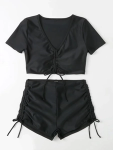 Detailed flat lay of black two-piece bikini featuring front drawstring ruched top and shorts