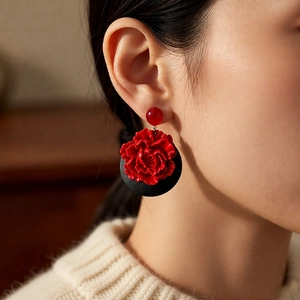 Detail of vintage wooden flower earrings with red and black design on female model