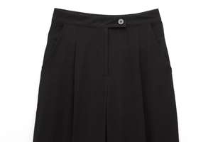 Dettaglio dei pantaloni neri a vita alta con pieghe, bottoni e tasche laterali