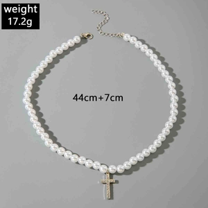 Detail of white pearl necklace with zircon-encrusted gold cross pendant and lobster clasp