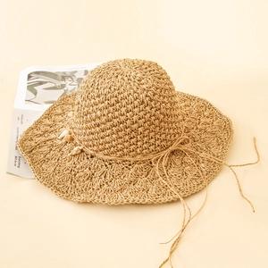 Handmade khaki straw sun hat with shell decor and bow on minimalist background