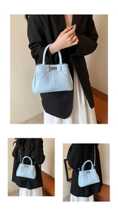 Detail of light blue textured leather handbag with decorative stitching and silver hardware