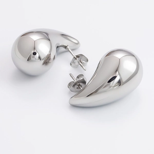 Macro shot of polished silver hollow teardrop earrings with a mirror-finish metal surface