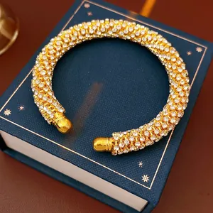 Luxurious gold-tone open cuff bracelet with pavé rhinestones and spherical metal ends