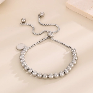 Détail d'un bracelet à perles argentées ajustable avec pendentif rond et billes polies