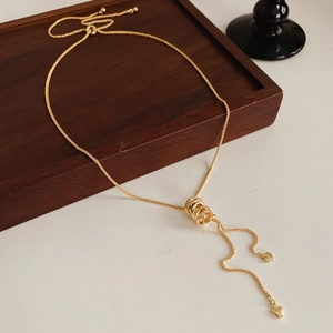 Detail of adjustable gold necklace with zircon circles and a heart pendant charm