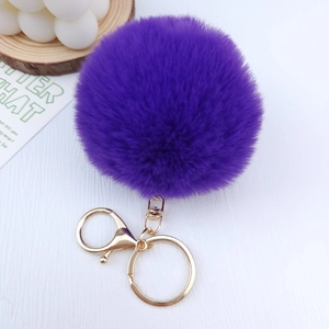 Detailed view of a purple faux fur pompom keychain with a gold-tone metal spring ring clasp