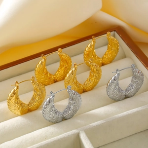 Golden and silver wing earrings with feather texture in a jewelry box