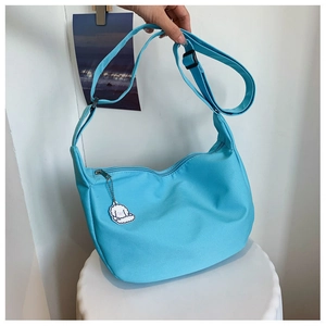Detail of light blue crescent bag with nylon texture and a cute dog charm attachment