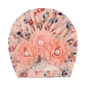 Detail of pink floral baby turban hat with decorative fabric flowers and center pearls