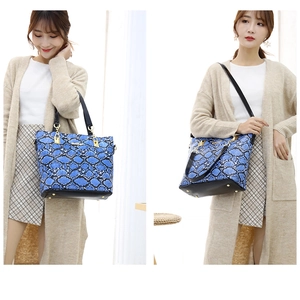 Detail of blue snakeskin tote bag featuring metallic hardware and protective bottom studs