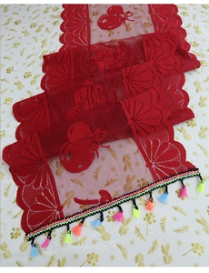Close-up of red Christmas lace table runner with festive embroidery and colorful tassels