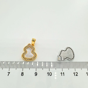 Macro view of gold puppy gourd pendant with seashell inlay and rhinestone detail