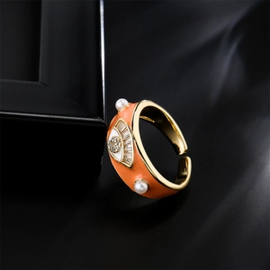 Golden evil eye ring with orange enamel, white pearls and AAA zirconias in diagonal view