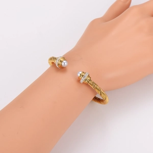 Golden twisted cable open bangle featuring white pearls and shimmering crystal accents