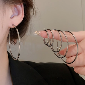 Comparison of different diameters for silver metal hoop earrings on a hand