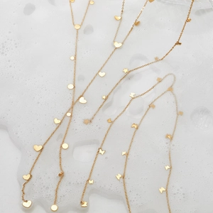 Golden Y-shaped necklaces with heart and star pendants on a clean soap bubble background