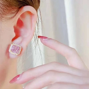 Close-up of elegant pink square gemstone earrings with gold halo setting on model