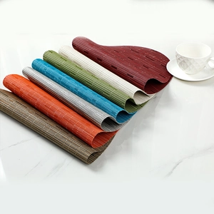 Set of oval bamboo texture PVC placemats in multiple colors on a marble surface