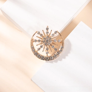 Macro detail of sun and moon vintage brooch with white crystals on gold base